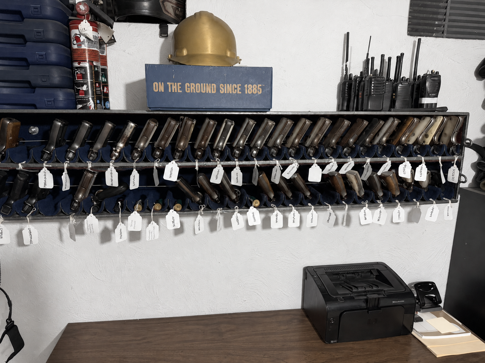 Estación de despacho de armamento con pistolas etiquetadas, radios de comunicación y equipo de protección